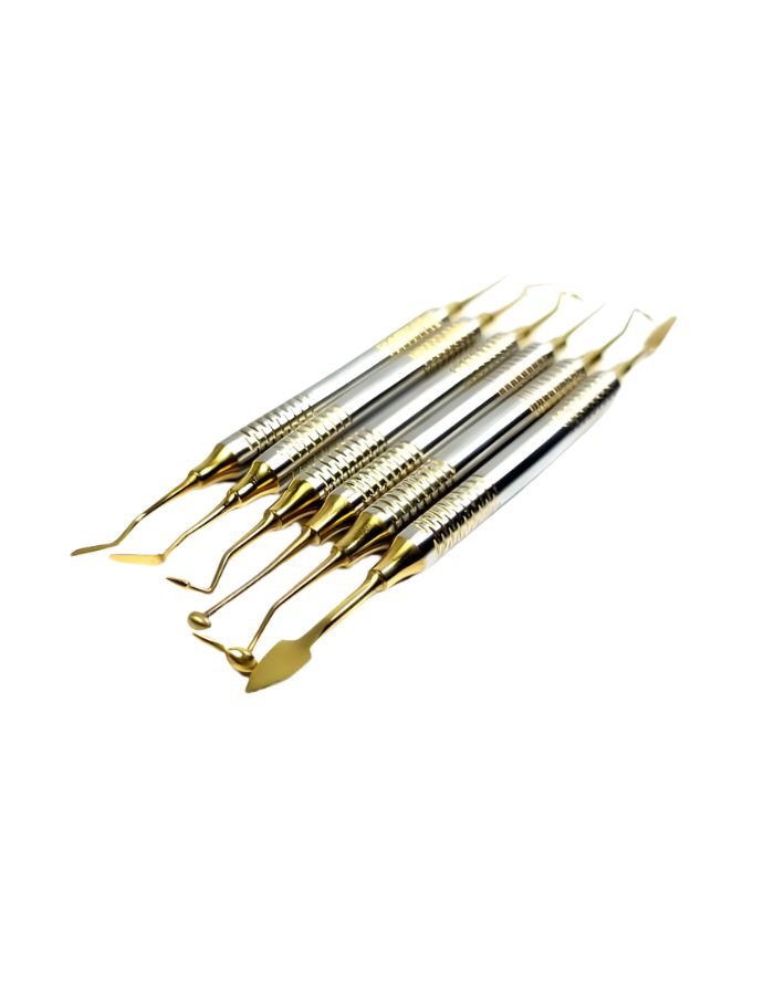 Set of dental tools with gold and silver handles on a white background